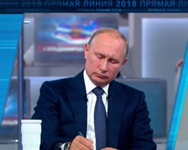 File Photo of Putin Sitting at Desk, Looking Down, Writing, During Call-In Show, adapted from screenshot of video at kremlin.ru