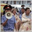 File Photo of Policeman with Bullhorn and Disaster Victims Wrapped in Blankets