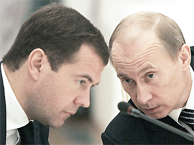 File Photo of Dmitry Medvedev and Vladimir Putin with Heads Bowed Over Microphone
