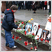 File Photo of Little Boy Leaving Flower by Informal Outdoor Memorial to Terrorism Victims Featuring Photos and Flowers