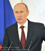 File Photo of Vladimir Putin Speaking with Flag Behind Him and Microphones in Front