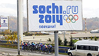 File Photo of Sochi Olympics Banner Near Highway in Warm Weather with Vehicle and Cyclicsts Nearby