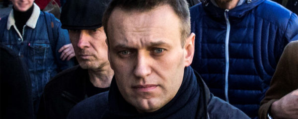 File Photo of Alexei Navalny Marching on Street with Others in Background; adapted from image at commons.wikimedia.org with credit to Evgeny Feldman, subject to Creative Commons license; original image at commons.wikimedia.org/wiki/File:FEV_1795_(cropped1).jpg, with license information at creativecommons.org/licenses/by-sa/4.0/deed.en and creativecommons.org/licenses/by-sa/4.0/legalcode
