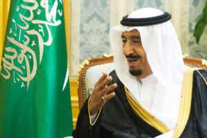 File Photo of King Salman of Saudi Arabia Seated Next to Saudi Flag and Gesturing, adapted from image at defense.gov
