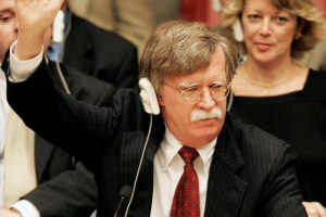 File Photo of John Bolton Raising Hand at United Nations, with United States Nameplate on Desktop in Front, adapted from image at state.gov