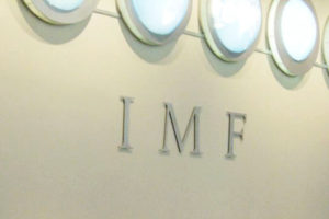 File Photo of IMF Acronym on Wall Below Row of Circular Lights, adapted from image at state.gov by Steven C. Welsh :: www.stevencwelsh.com :: www.stevencwelsh.info