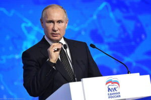 File Photo of Vladimir Putin at Podium with United Russia Logo, Gesturing