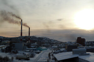 File Photo of Smokestacks Spewing Pollution in Murmansk, Russia, at twilight or before dawn, adapted from image at pnnl.gov with photo credit to N. Kholod