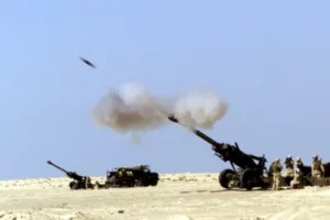 File photo of 88mm howitzers and troops in field, with shell in mid-flight, adapted from image at defense.gov