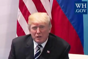 Cropped Photo of Donald Trump Seated In Front of U.S. and Russian Flags, Part of Larger Photo at Summit with Vladimir Putin, adapted from White House photo