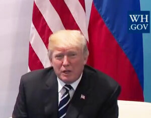 Cropped Photo of Donald Trump Seated In Front of U.S. and Russian Flags, Part of Larger Photo at Summit with Vladimir Putin, adapted from White House photo