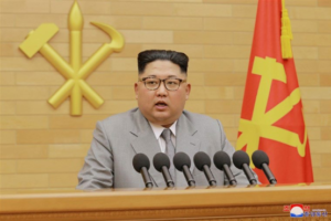 File Photo of Kim Jong-Un At Podium Near North Korean Flag and Hammer and Sickle Emblem, adapted from hhs.gov image