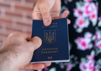 File Photo of Ukraine Passport Passed Between Hands and Lady's Dress with Brick Wall in Background, adapted from hhs.gov image